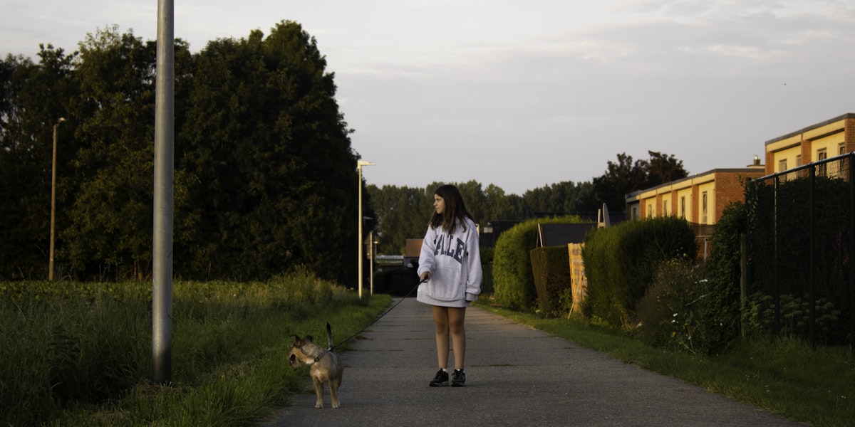 A teenager walking a dog along a neighborhood path